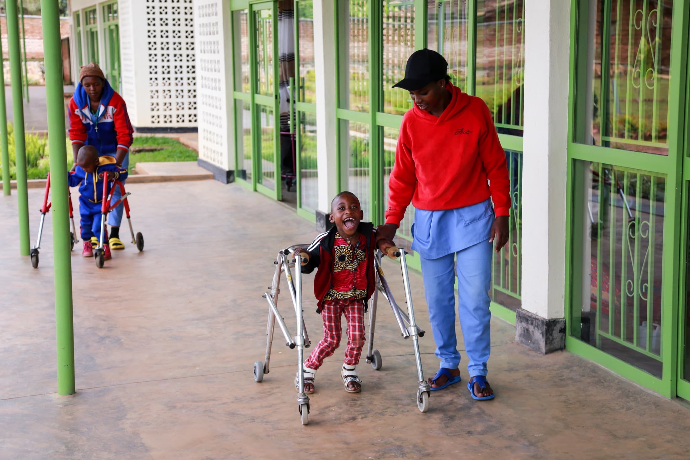 A child smiling while practicing walking with a physiotherapist at a Journeyman-designed center