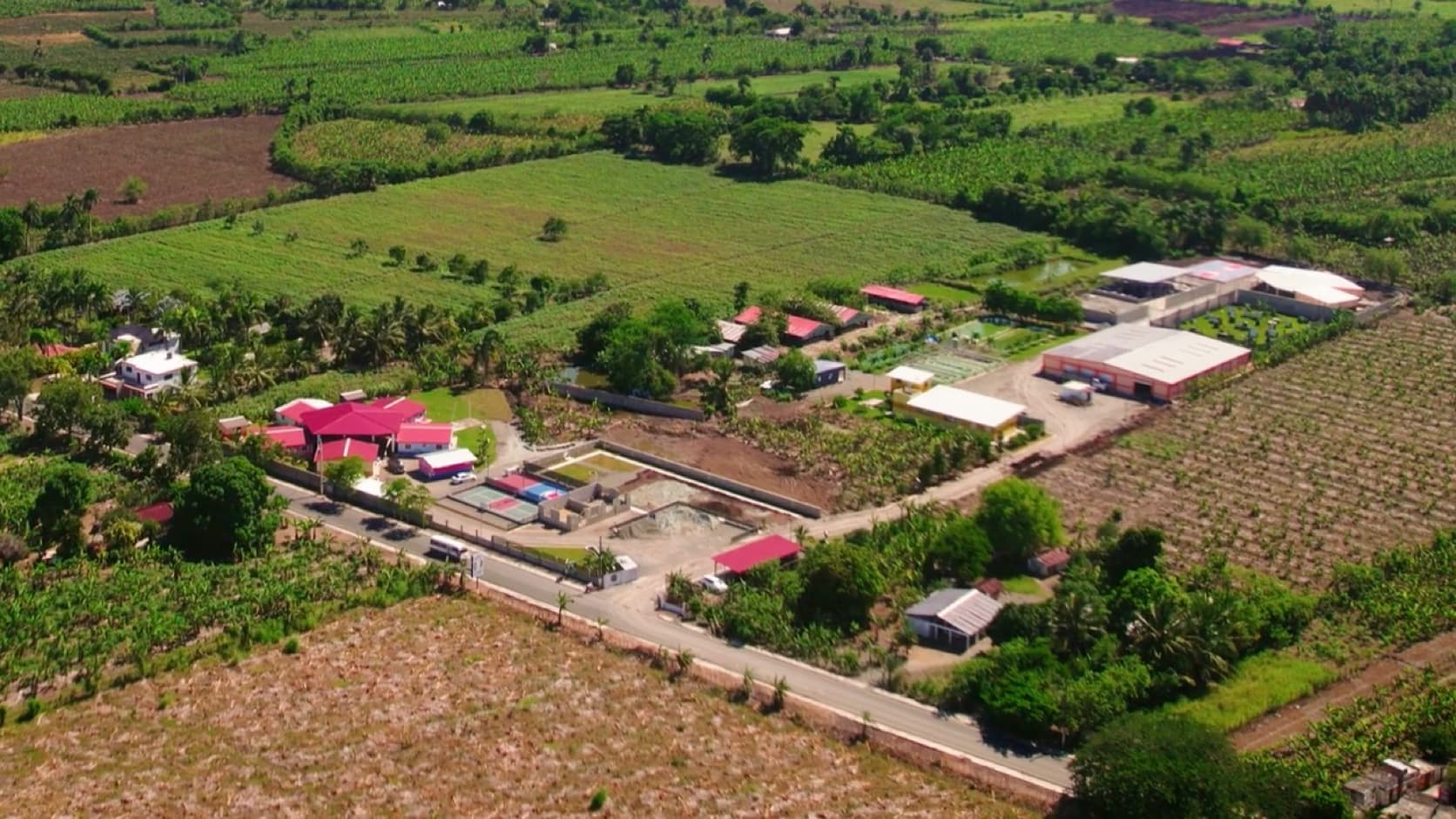 Aerial photograph of the M2535 Vocational Village campus, productive fields, aquaponics systems, and completed buildings in Santiago
