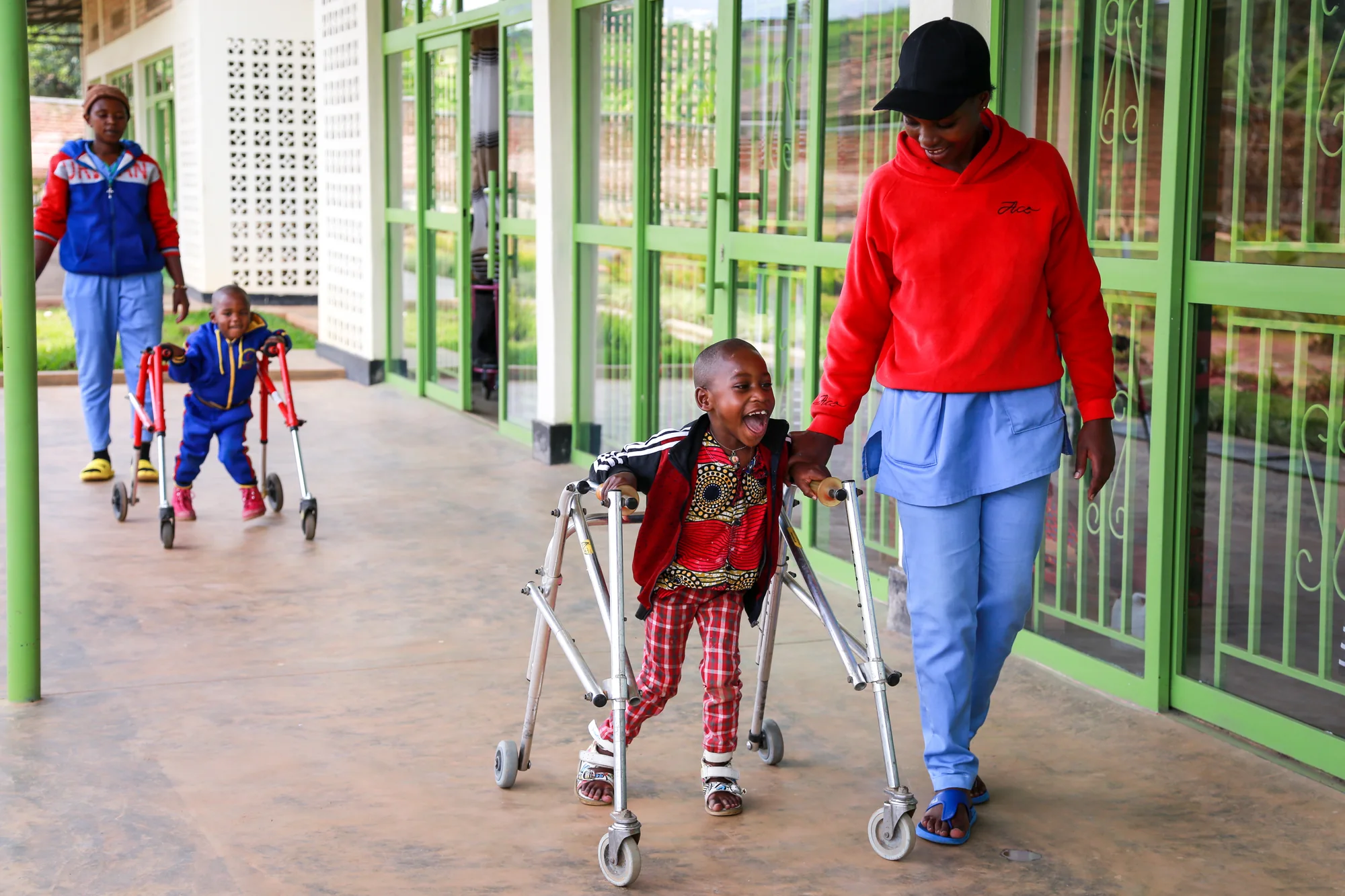 Therapy staff supporting young patients as they practice walking along the ASFA center's covered veranda