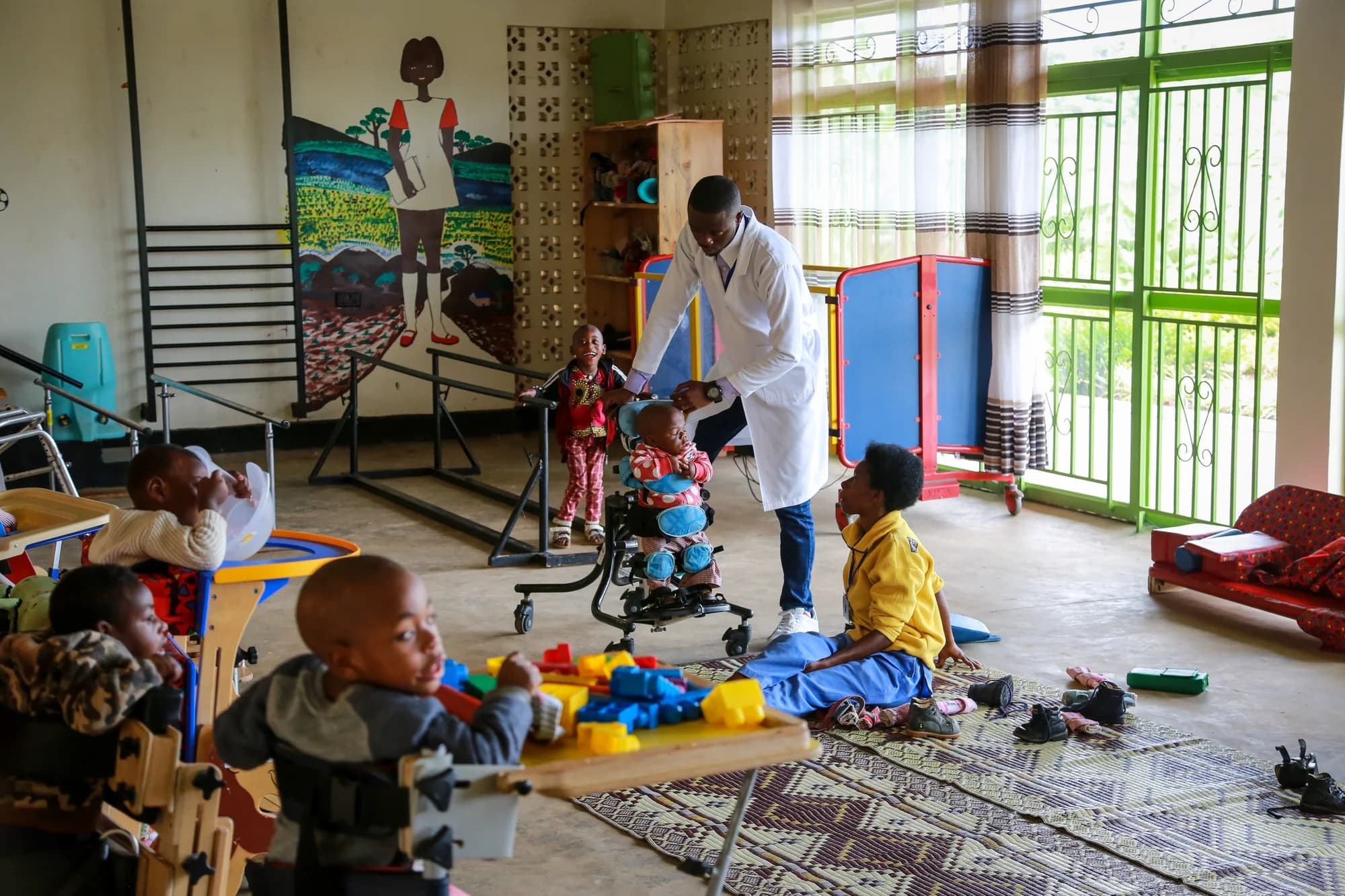 A therapist and care staff supporting young patients during a physiotherapy session inside the ASFA center