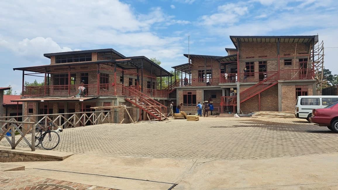 The Azizi Life Guesthouse courtyard under construction, with completed brick walls, shaded galleries, and landscaped gathering space