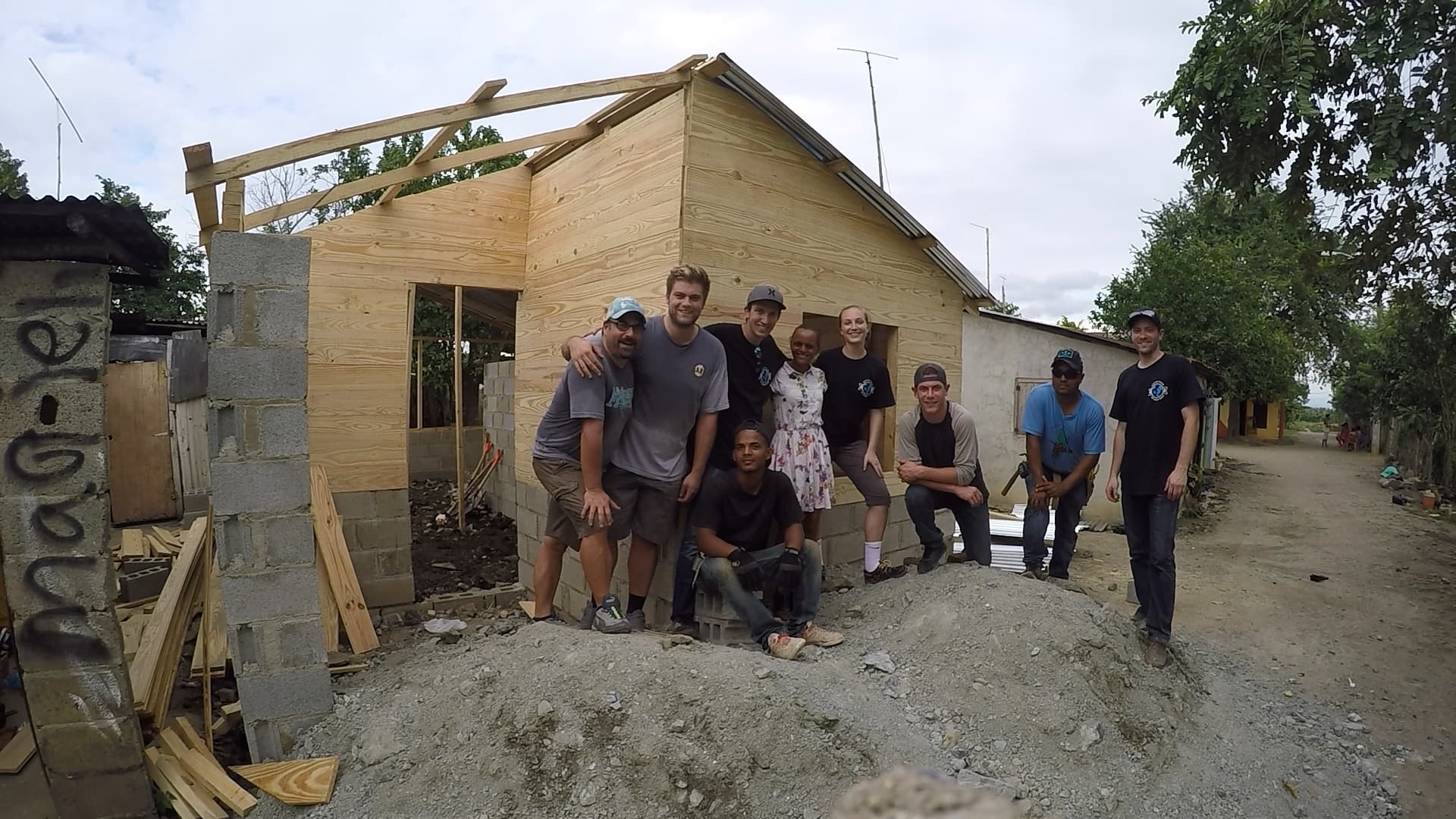 The M2535 project team gathered beside a small timber and masonry building under construction
