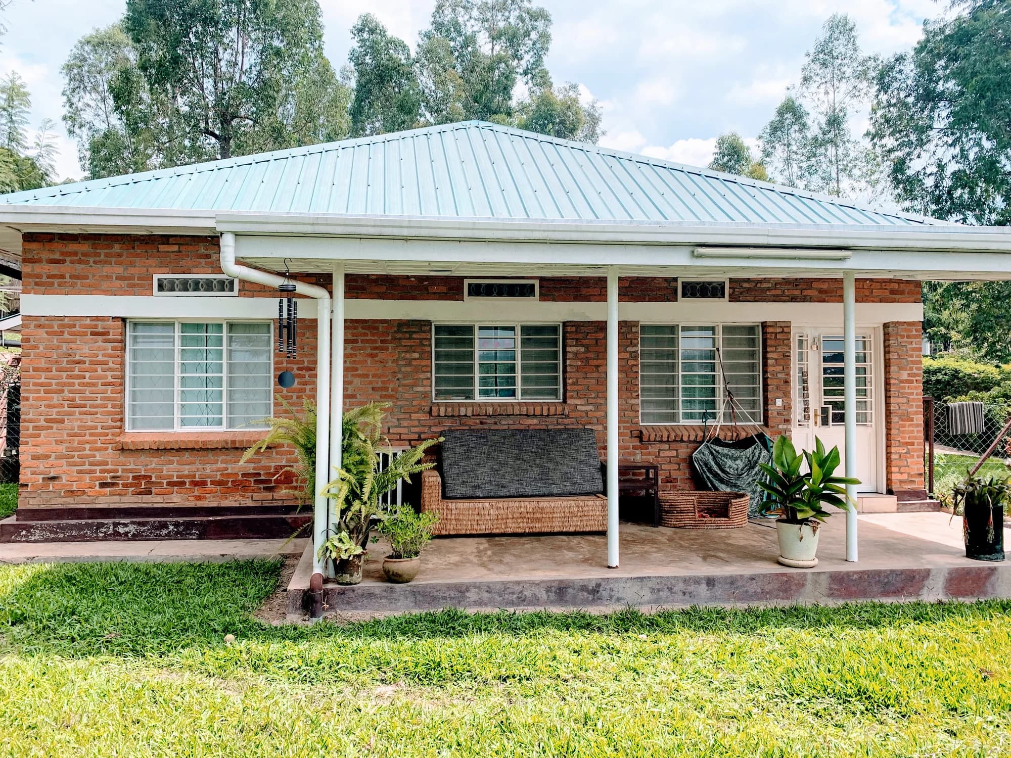 The completed guesthouse veranda wrapping the brick residence and opening toward the garden