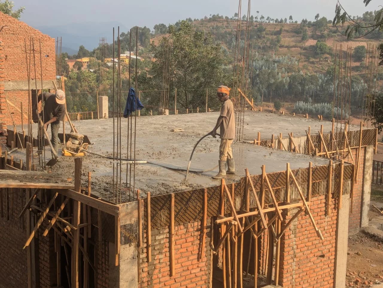 Builders place and finish a reinforced-concrete slab at the Sunzu Multipurpose Community Center above Rwanda's Burera hills