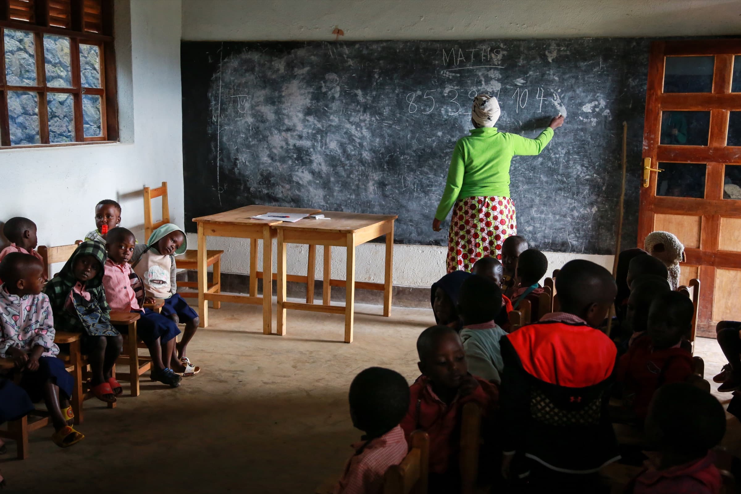A teacher leading a mathematics lesson in the Sunzu Village library classroom